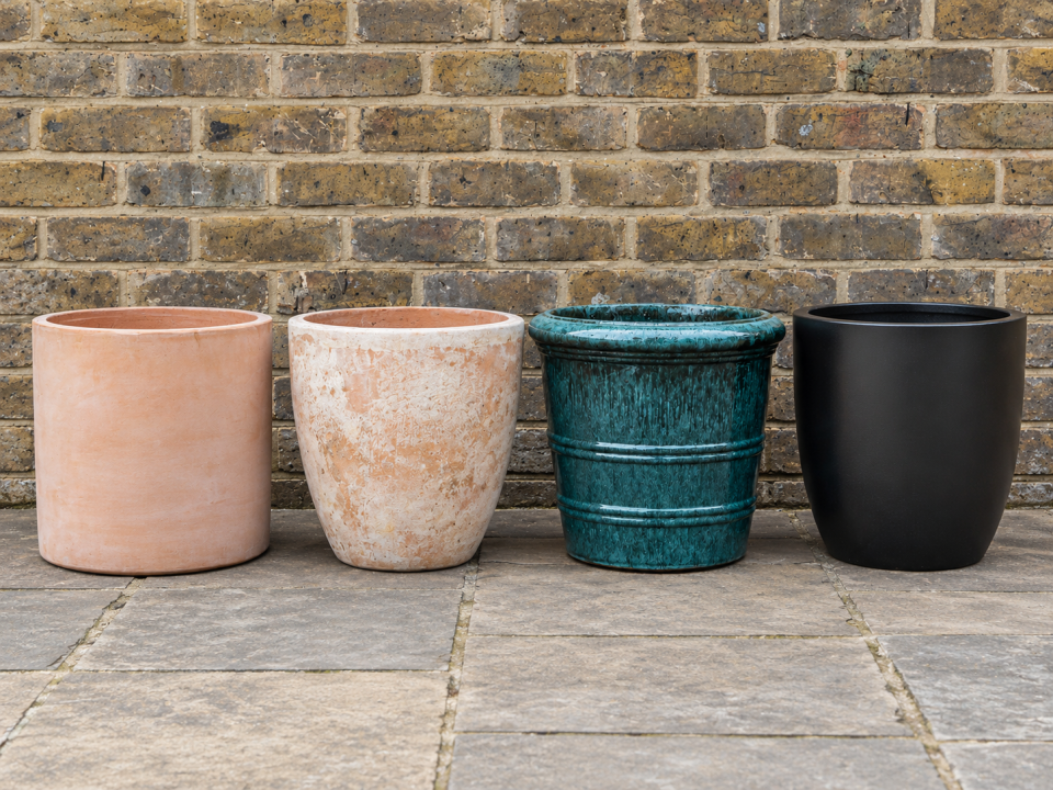 Plain terracotta, aged terracotta, glazed terracotta and polystone pots shown side by side, illustrating the contrast in finish